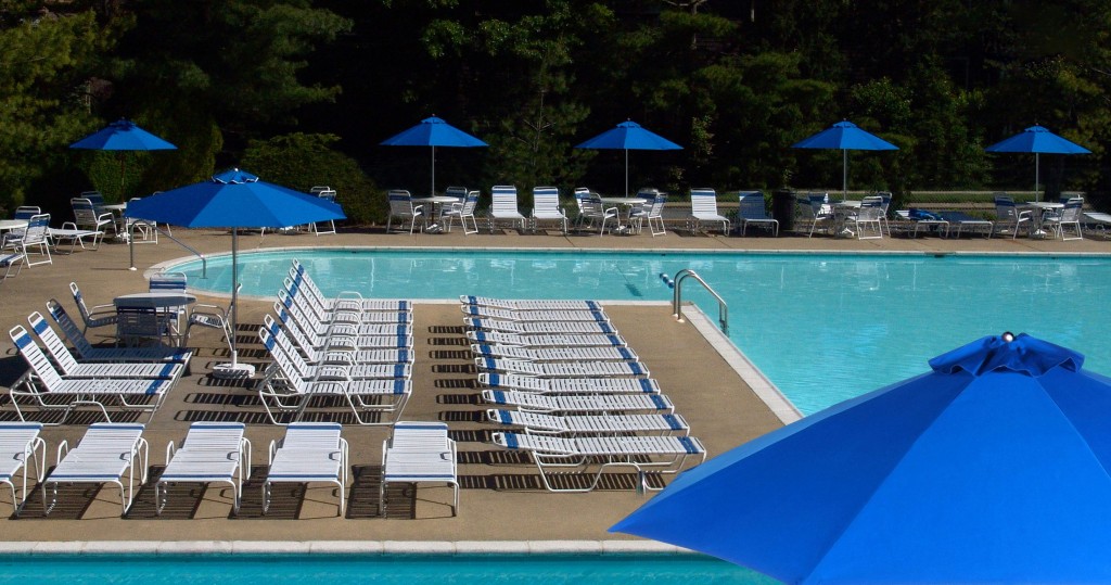 A resort pool with a lot of chairs and umbrellas beside it - Resort Contract Furnishings
